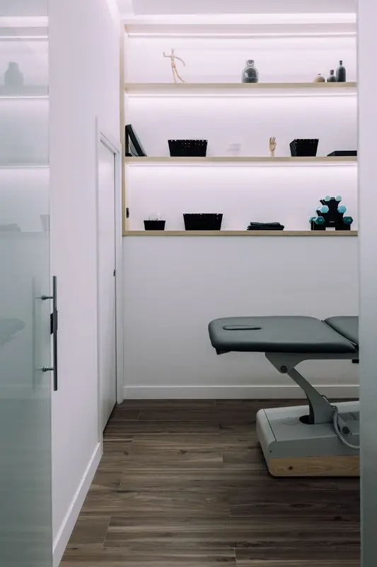 Camilla eléctrica y estanterías de material de fisioterapia