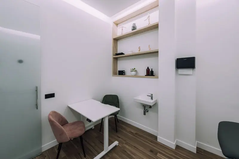 Zona de valoración con escritorio y lavabo en la sala de tratamiento