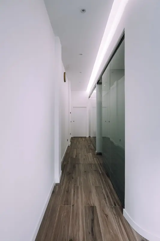Pasillo de la clínica con luz indirecta y suelo de madera
