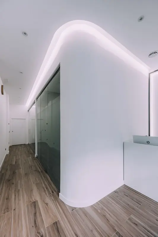 Pasillo curvo con luz indirecta hacia la recepción
