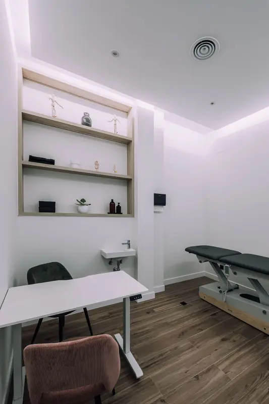 Sala de tratamiento con camilla, escritorio y estanterías