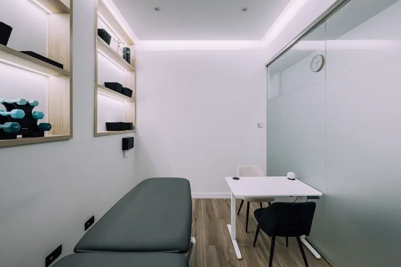 Sala de tratamiento con camilla, mesa y material de ejercicio
